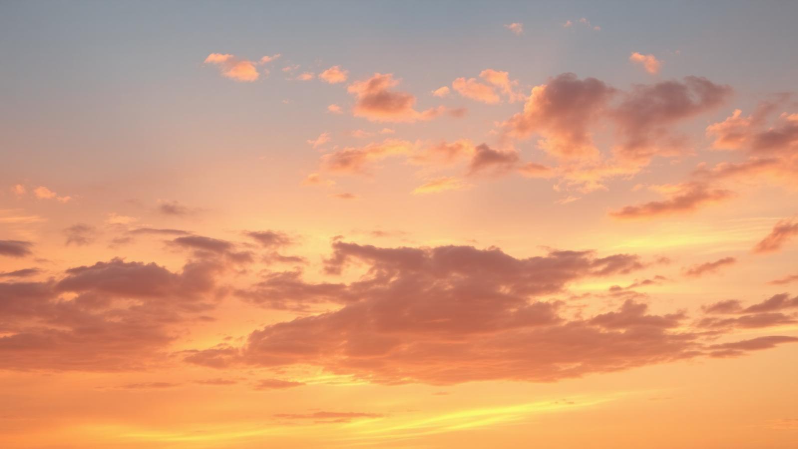 Peach sky at dawn with soft clouds
